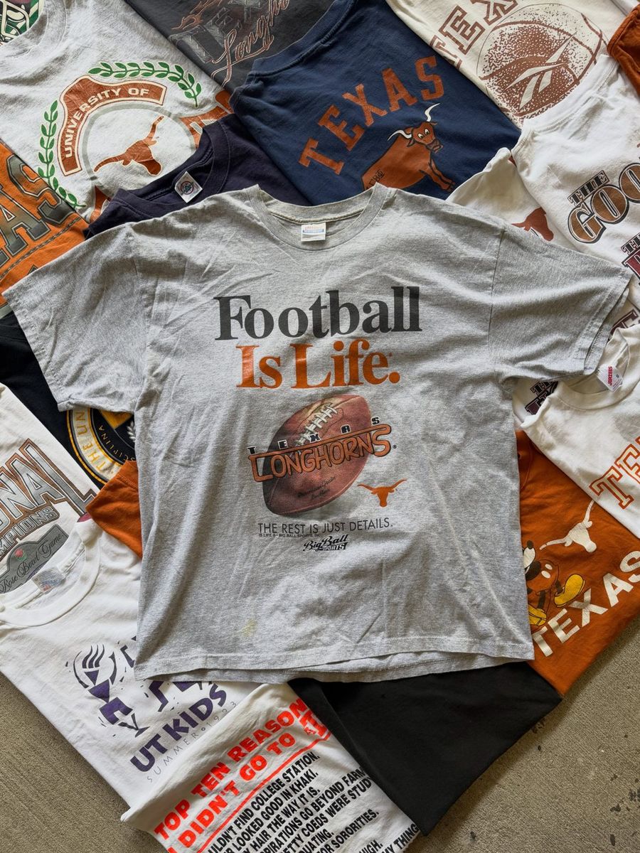 Football Is Life vintage tee on a stack of Longhorns shirts