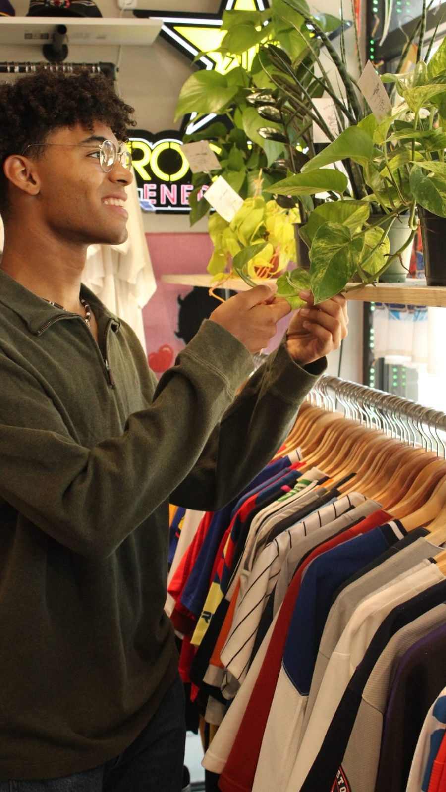 Shopper checking out plants for sale by a neon sign