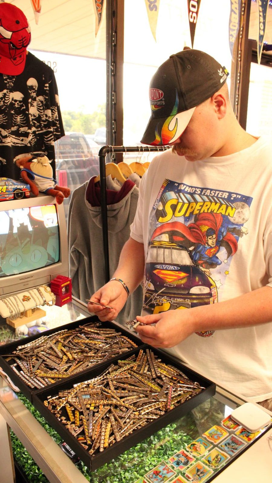 Shopper in a NASCAR Superman Who's Faster tee and a DuPont flame hat